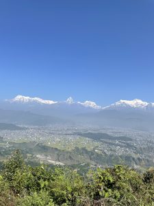 A wide view of Pokhara valley, with the city below, green hills, and lush surroundings.