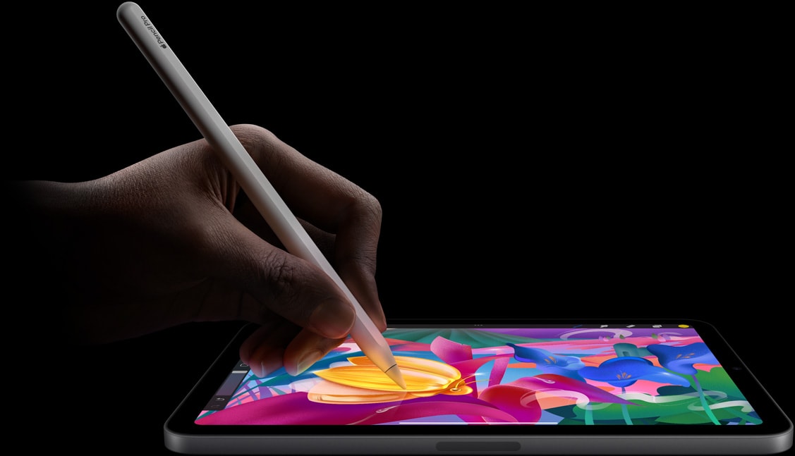 Mâna unui utilizator care ține un Apple Pencil Pro și creează artă plină de culori pe iPad mini.